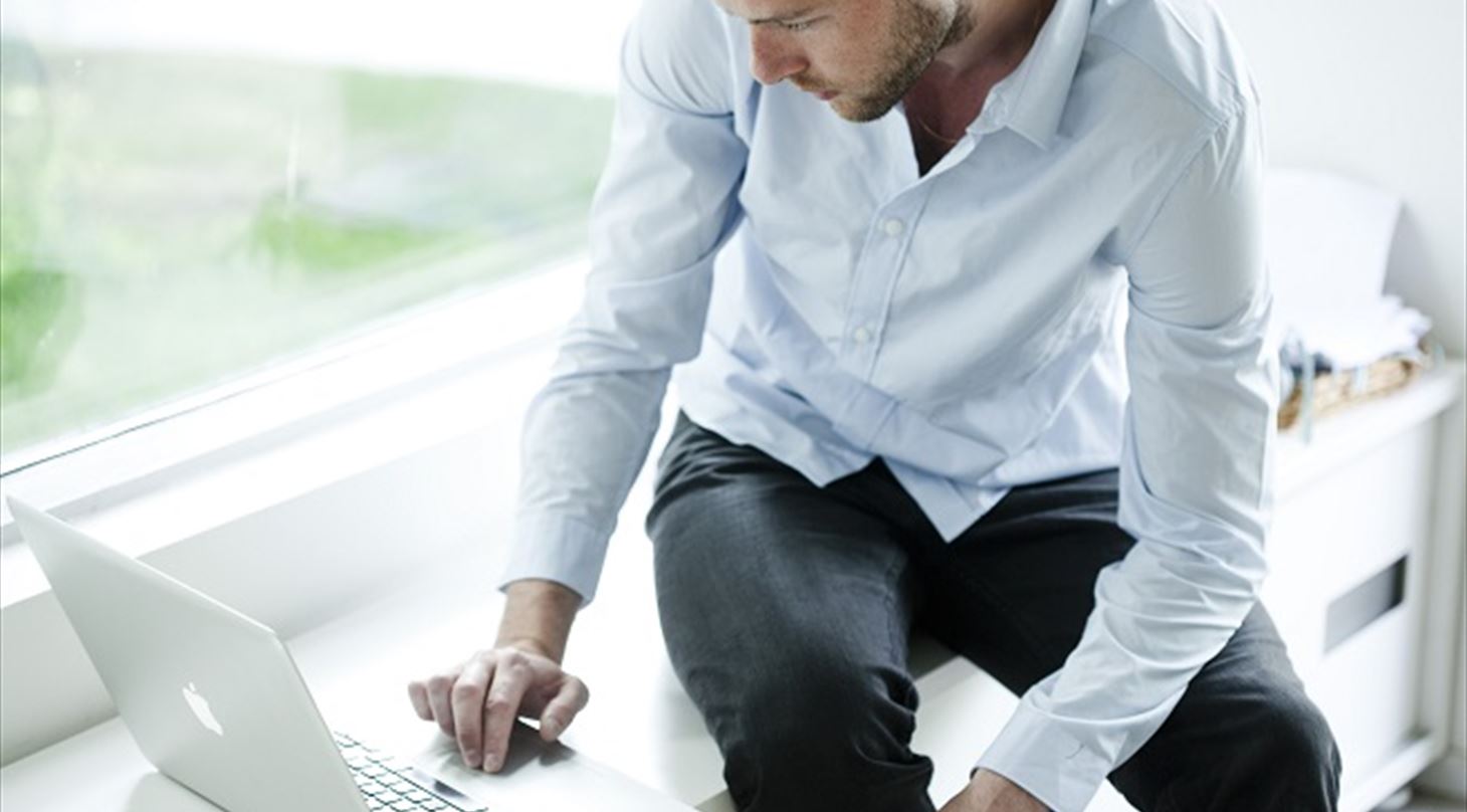 Billedet viser en mand med en computer